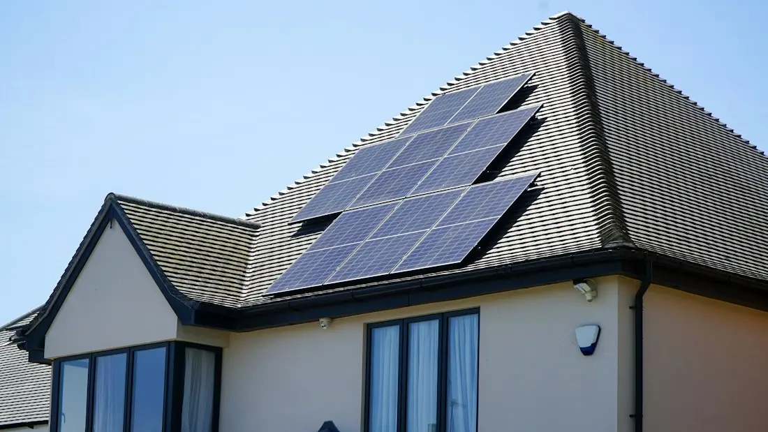 Casa con placas solares en el tejado bajo un cielo azul